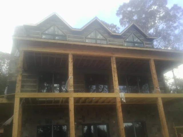 Dormers and porch framing on a large log home under construction — Roof Coating work by our crew in Plano
